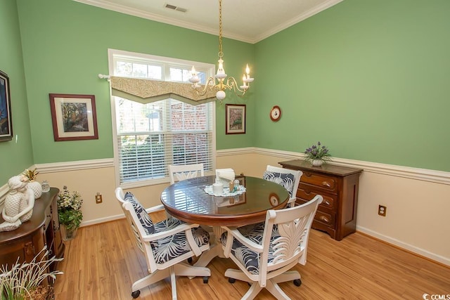 dining space featuring light hardwood / wood-style flooring, crown molding, and a notable chandelier