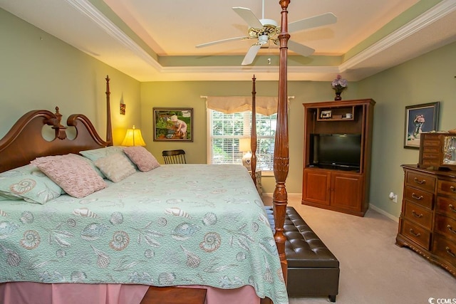 bedroom featuring ceiling fan, light colored carpet, ornamental molding, and a tray ceiling