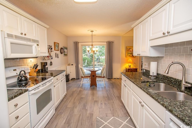 kitchen with white appliances, sink, hanging light fixtures, light wood-type flooring, and a notable chandelier