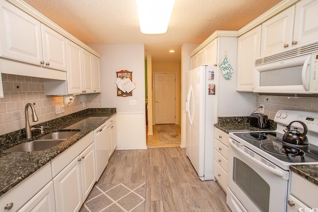 kitchen featuring a textured ceiling, sink, white appliances, and light hardwood / wood-style flooring