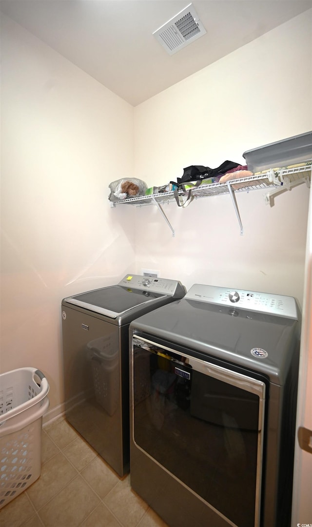 laundry room with washer and clothes dryer and light tile patterned floors