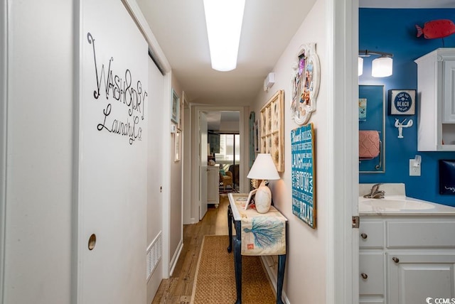 corridor featuring light hardwood / wood-style flooring and sink