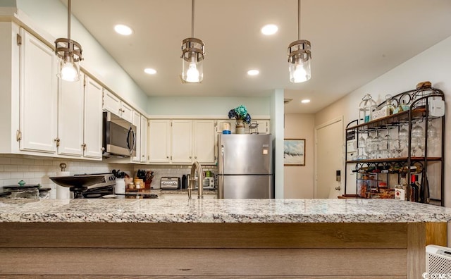 kitchen with appliances with stainless steel finishes, tasteful backsplash, white cabinetry, and pendant lighting