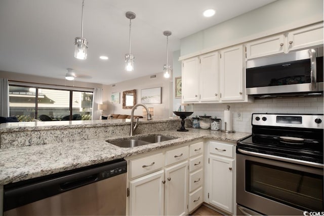 kitchen featuring pendant lighting, white cabinets, sink, appliances with stainless steel finishes, and tasteful backsplash