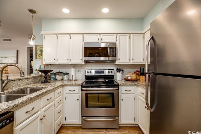 kitchen featuring light stone countertops, sink, pendant lighting, white cabinets, and appliances with stainless steel finishes