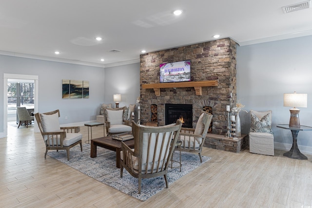 living room featuring light hardwood / wood-style floors, a stone fireplace, and ornamental molding