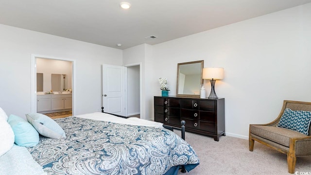 bedroom with ensuite bath and light colored carpet