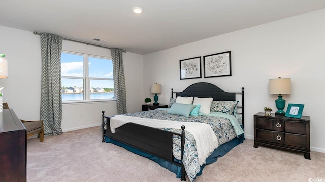 bedroom featuring a water view and light colored carpet