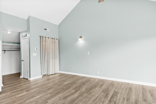 unfurnished bedroom with a closet, high vaulted ceiling, and light hardwood / wood-style flooring