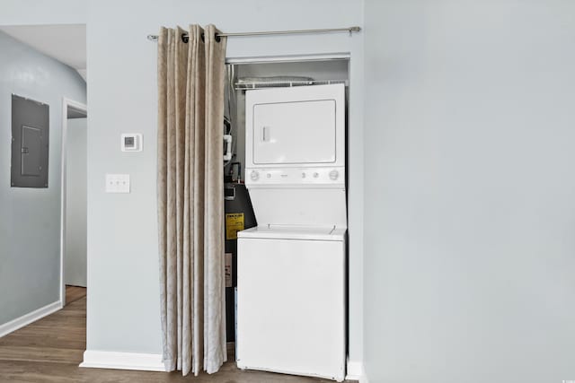 clothes washing area with hardwood / wood-style flooring, stacked washer / drying machine, and electric panel