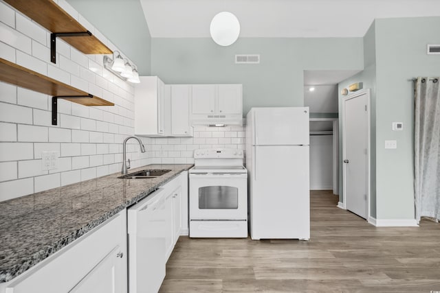 kitchen featuring white appliances, dark stone counters, white cabinets, sink, and light hardwood / wood-style floors