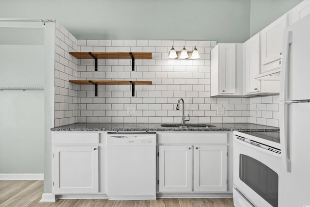 kitchen with white appliances, dark stone counters, sink, light hardwood / wood-style flooring, and white cabinetry