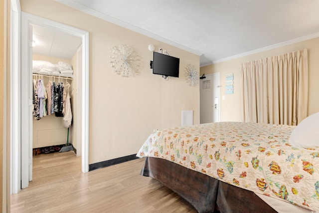 bedroom with a walk in closet, hardwood / wood-style flooring, a closet, and ornamental molding