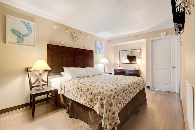 bedroom with light hardwood / wood-style floors, a textured ceiling, and ornamental molding