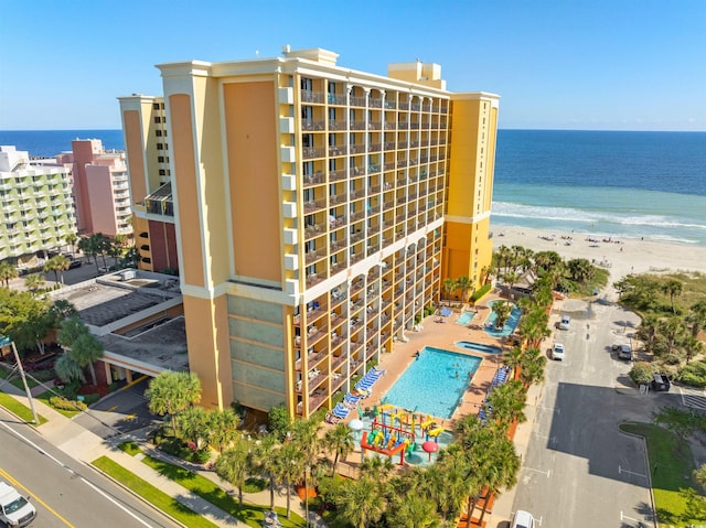 view of property featuring a community pool, a water view, and a view of the beach