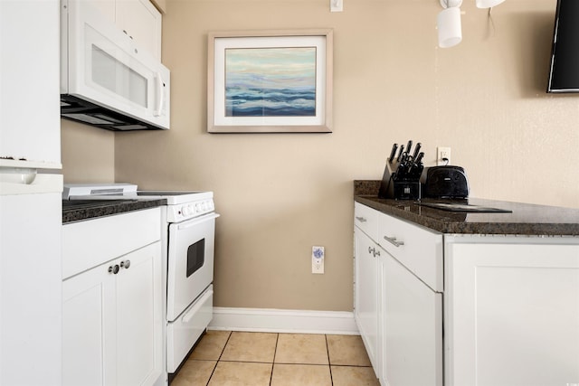 kitchen with light tile patterned floors, white cabinets, dark stone counters, and white appliances