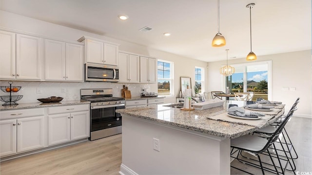 kitchen with a center island, stainless steel appliances, white cabinetry, and plenty of natural light