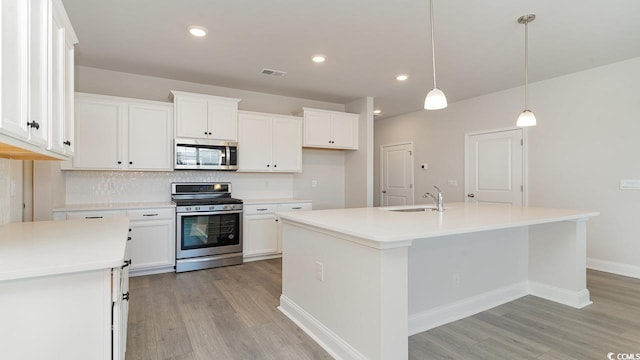 kitchen with a kitchen island with sink, stainless steel appliances, a sink, visible vents, and light wood-type flooring