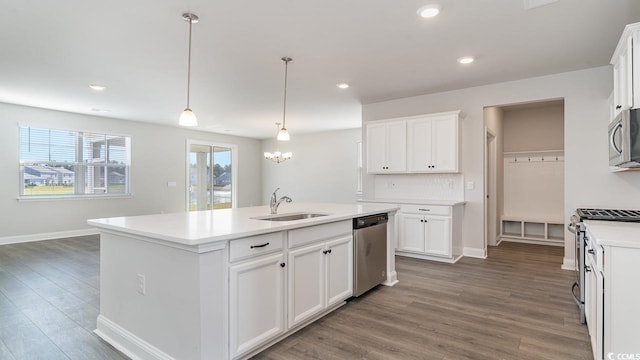 kitchen with stainless steel appliances, light countertops, white cabinetry, a sink, and wood finished floors