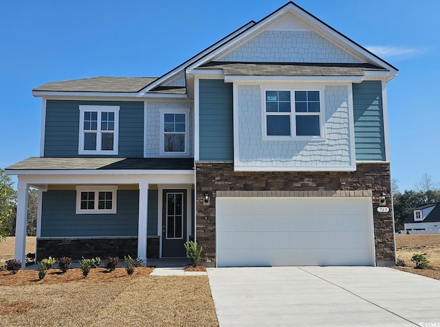 craftsman-style home with an attached garage, stone siding, covered porch, and concrete driveway