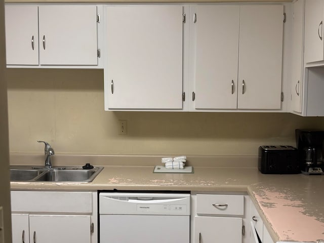 kitchen with white dishwasher, white cabinetry, and sink