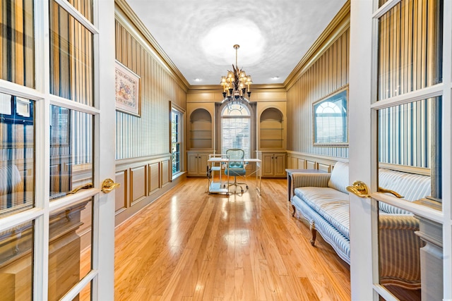 unfurnished room with a chandelier, crown molding, and light hardwood / wood-style flooring