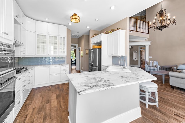 3754 Annandale Dr, Myrtle Beach, SC 29577 - kitchen with stainless steel appliances, a peninsula, a breakfast bar area, dark wood-style flooring, and glass insert cabinets