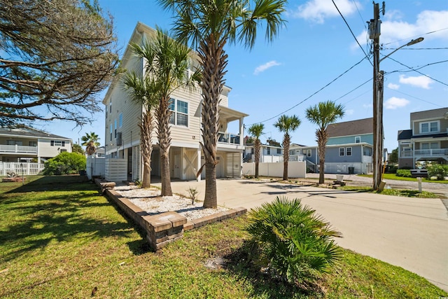 exterior space featuring fence, driveway, a lawn, a residential view, and a carport