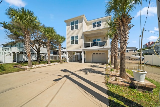 coastal home featuring a carport, concrete driveway, a garage, and stairs