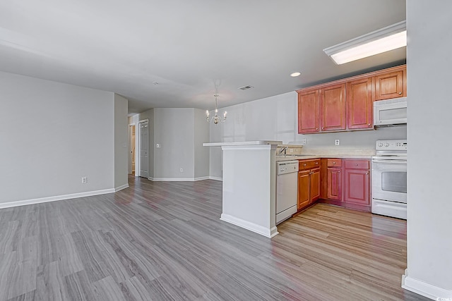 kitchen with kitchen peninsula, a chandelier, white appliances, and light wood-type flooring