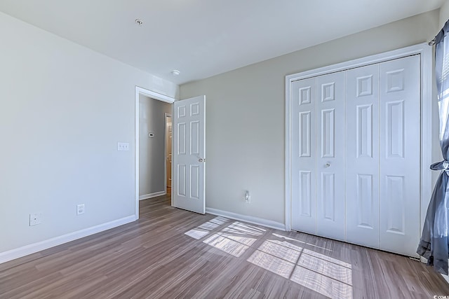 unfurnished bedroom with light wood-type flooring and a closet