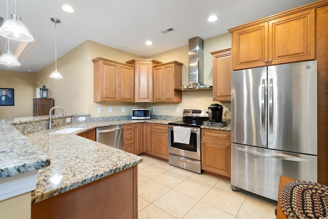 kitchen with sink, wall chimney exhaust hood, stainless steel appliances, light stone counters, and decorative light fixtures