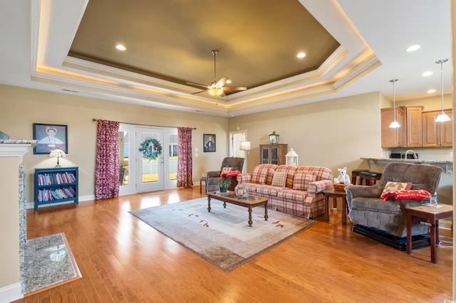 living room featuring light hardwood / wood-style floors, a raised ceiling, ceiling fan, and crown molding