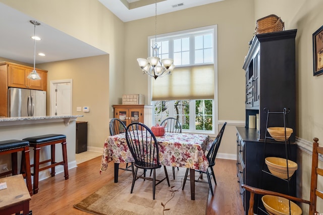 dining room with light hardwood / wood-style flooring and a notable chandelier