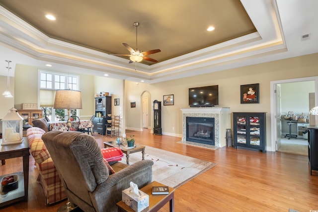 living room featuring light wood-type flooring, a raised ceiling, and ceiling fan