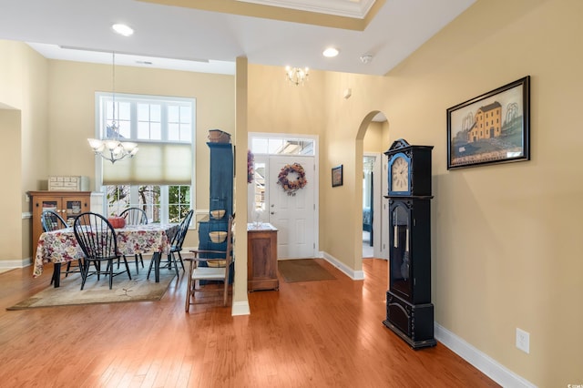 entrance foyer with wood-type flooring, ornamental molding, and a chandelier