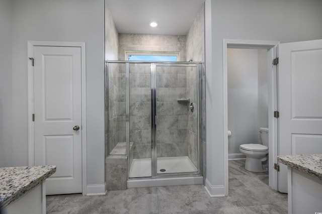 bathroom featuring a shower with door, vanity, and toilet