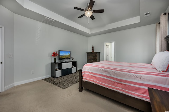 carpeted bedroom featuring ceiling fan and a raised ceiling