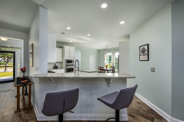 kitchen featuring kitchen peninsula, stainless steel appliances, a wealth of natural light, and dark wood-type flooring