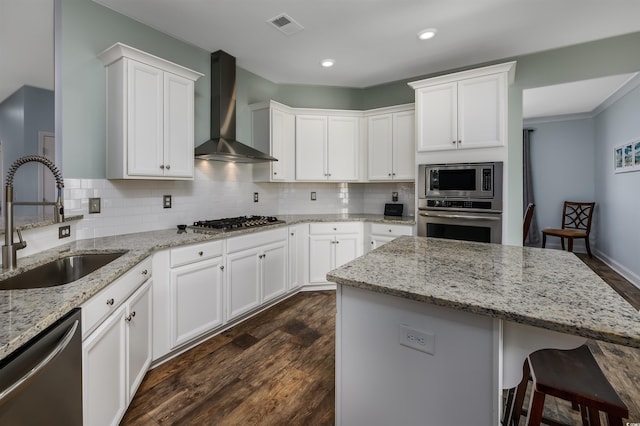 kitchen featuring white cabinets, wall chimney range hood, dark wood-type flooring, and appliances with stainless steel finishes