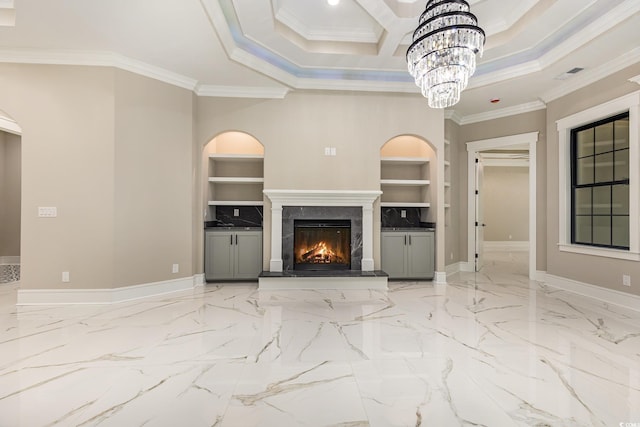 unfurnished living room with a raised ceiling, a premium fireplace, built in features, a notable chandelier, and crown molding