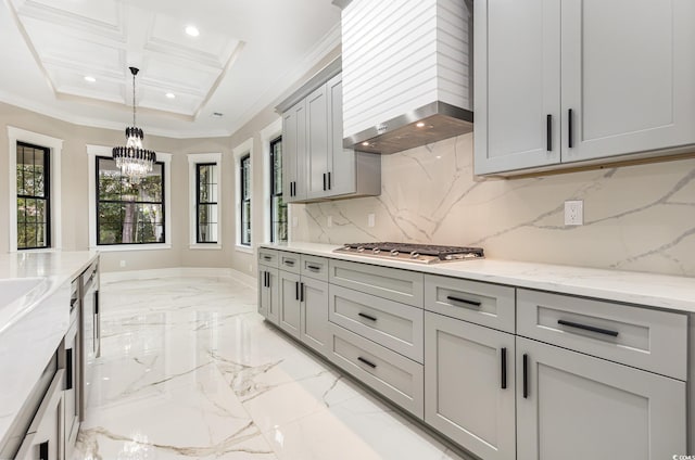 kitchen with light stone countertops, wall chimney exhaust hood, crown molding, stainless steel gas stovetop, and gray cabinets