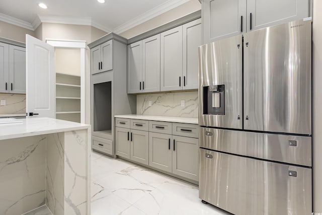 kitchen featuring light stone countertops, tasteful backsplash, stainless steel fridge, crown molding, and gray cabinets