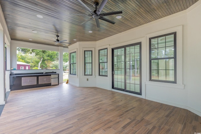 unfurnished sunroom featuring ceiling fan, wood ceiling, and sink