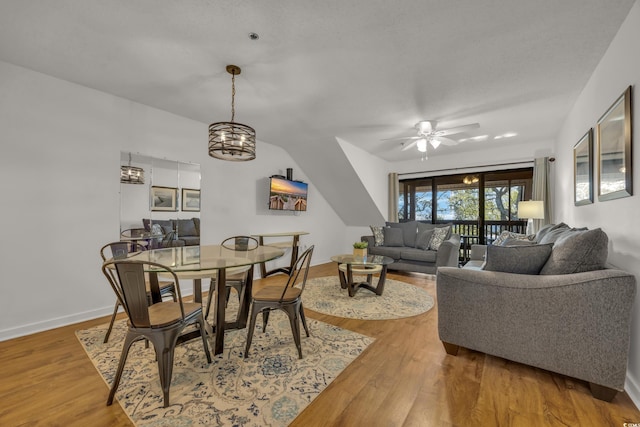 dining room with hardwood / wood-style floors and ceiling fan with notable chandelier