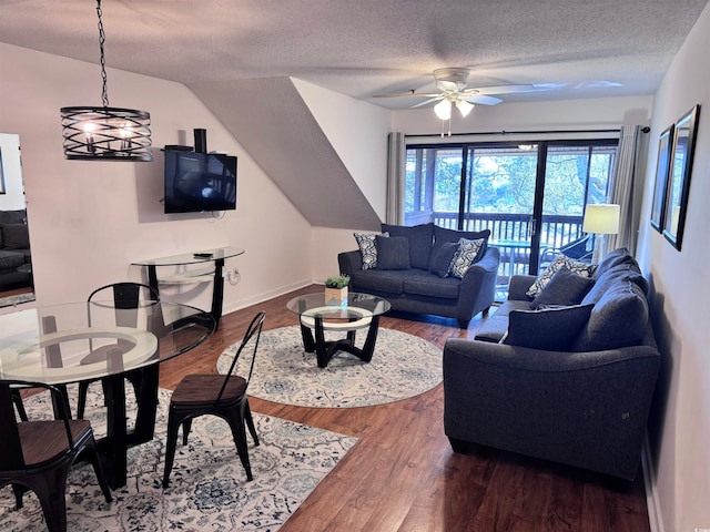 living room featuring ceiling fan with notable chandelier, wood-type flooring, and a textured ceiling