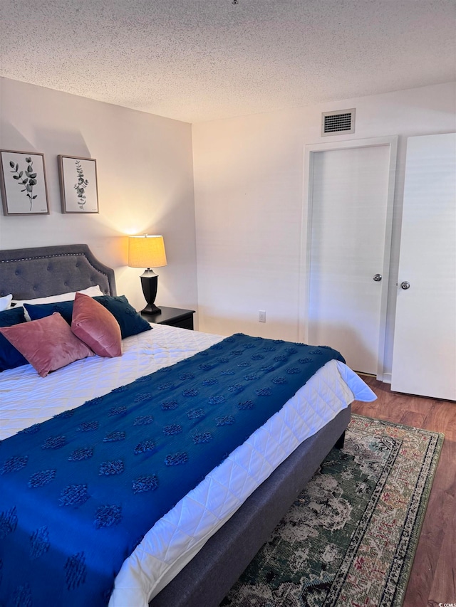 bedroom with wood-type flooring and a textured ceiling