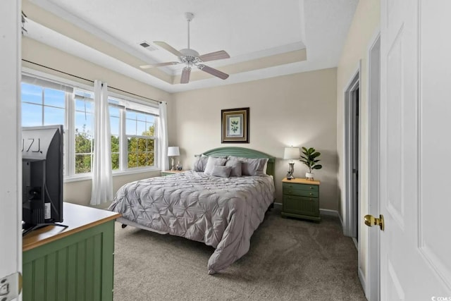 carpeted bedroom with a tray ceiling and ceiling fan