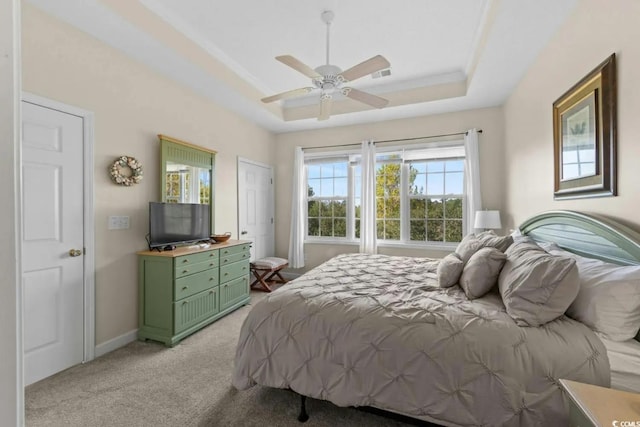 bedroom with ceiling fan, light colored carpet, and a tray ceiling