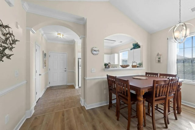 dining room featuring hardwood / wood-style floors, ornamental molding, lofted ceiling, and a notable chandelier